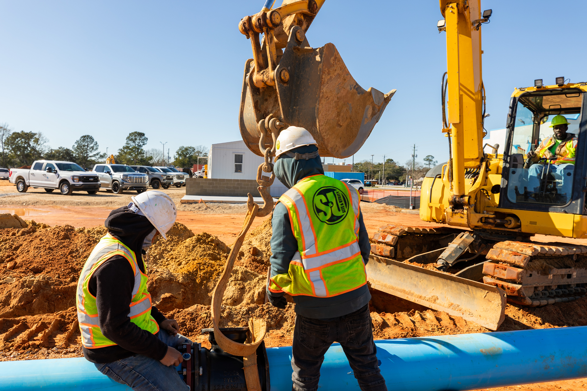 Site & Utility crew setting a water main with an excavator